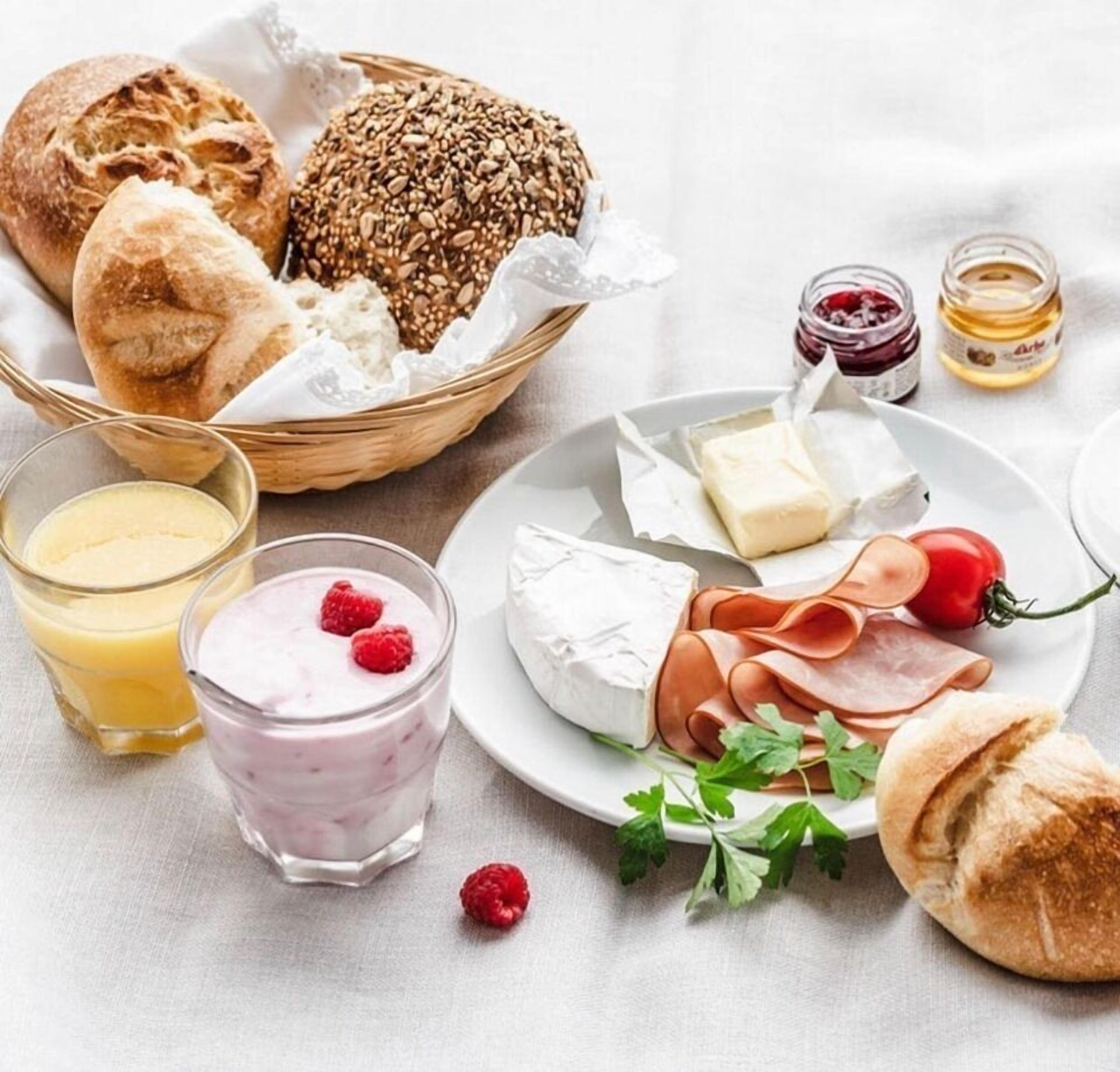 Ein Frühstücksbuffet mit Brot, Käse, Schinken und einem Glas Saft.