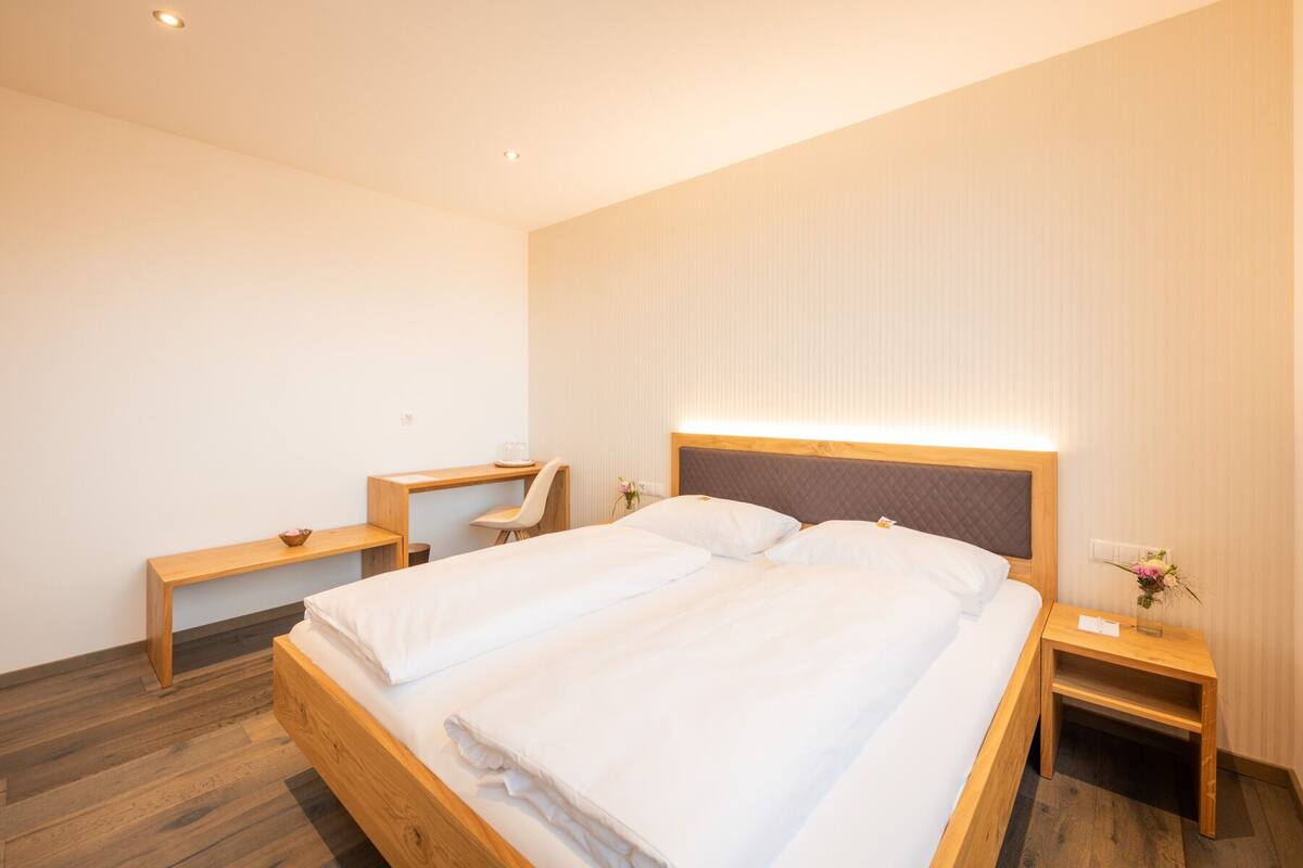 Una habitación de hotel moderna con una cama de madera, un escritorio y una silla.