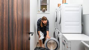 Une buanderie équipée d’un lave-linge, d’un sèche-linge et de plusieurs sèche-linge superposés.