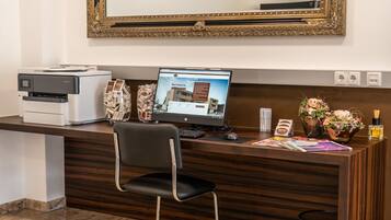 En hotelreception med en computer, printer og en stol.