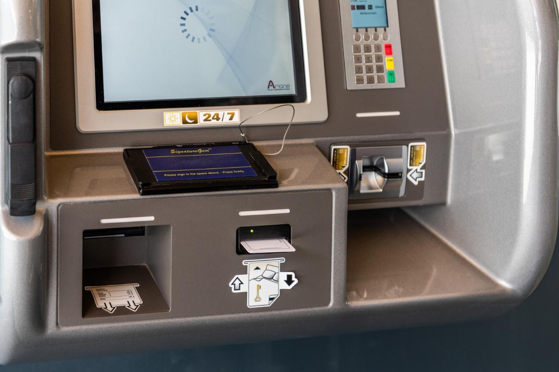 An ATM machine with a digital display, a keypad, and a signature card reader.