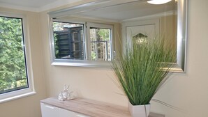 A room with a large window, a white cabinet with drawers, and a tall green plant on top. - Apartment With Private Terrace (Harzgerode)