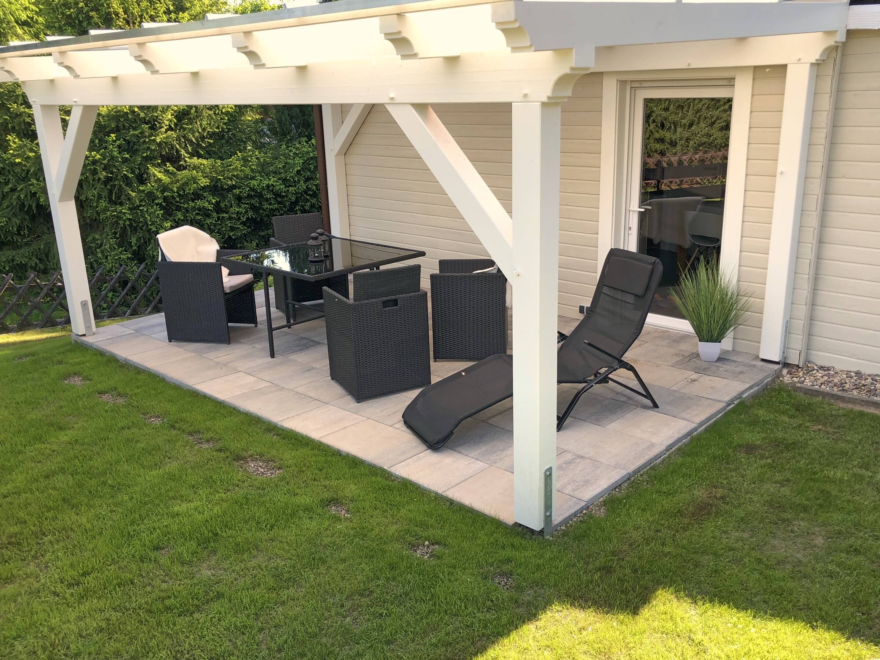 Un portico coperto con tavolo e sedie, circondato da una pergola bianca.