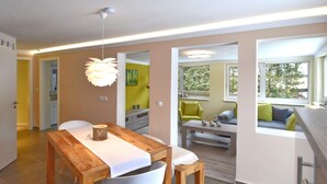 A modern kitchen with a wooden table, white chairs, and a hanging light fixture. - Apartment With Private Terrace (Harzgerode)