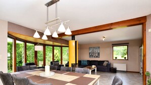 A spacious living room with a large wooden dining table, multiple chairs, a sofa, and a fireplace. - Beautiful Holiday Home in Durbuy With Garden (Durbuy)
