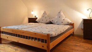 Un lit en bois, recouvert d’une couvre-lit à motifs et agrémenté de deux oreillers à pois, avec deux tables de chevet surmontées de lampes.