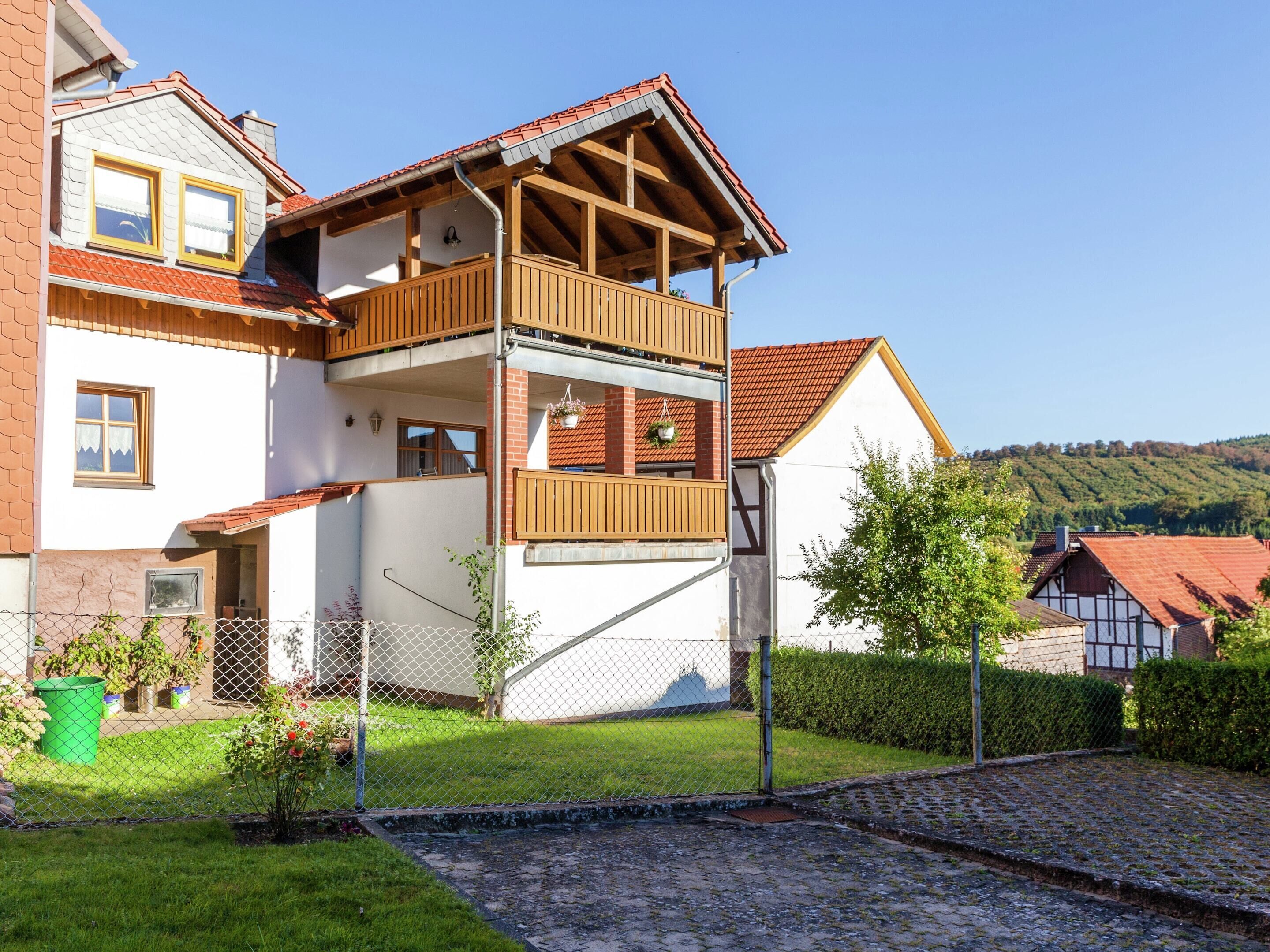 A two-story house with a balcony, a garden, and a cobblestone path.