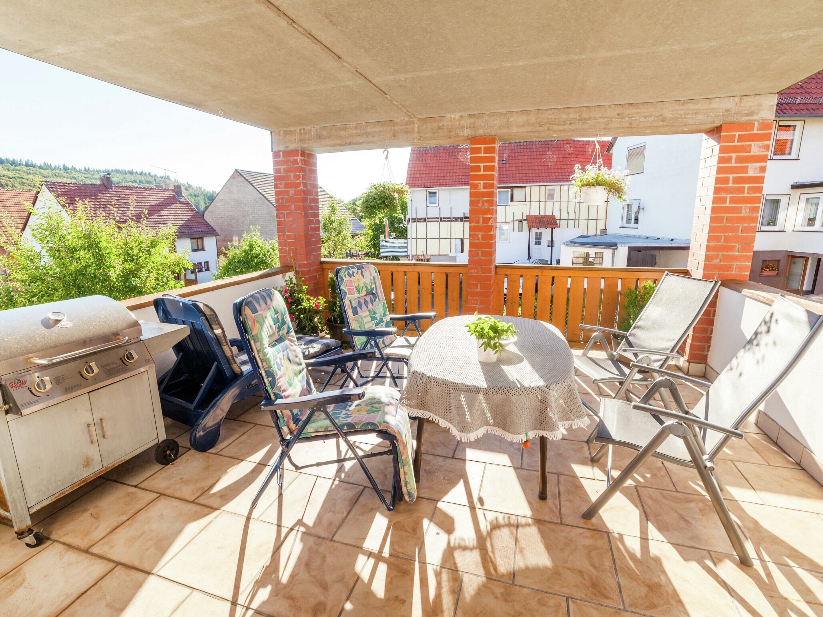 A covered patio with a grill, outdoor seating, and a view of houses.