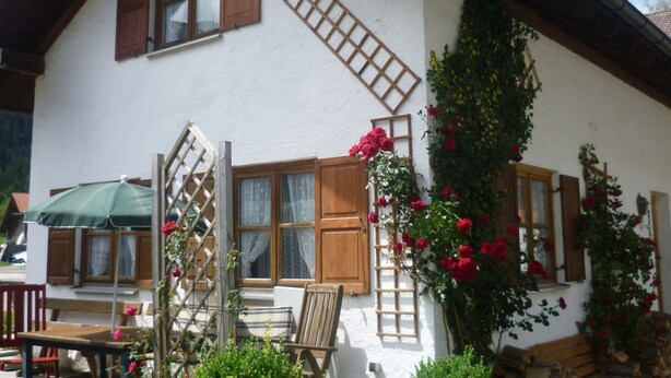A traditional chalet with wooden shutters, a balcony with a lattice, and a rose bush climbing the wall. - Retreat in the Ammergau Alps (Unterammergau)