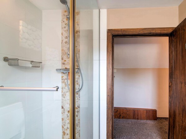 A bathroom with a glass shower enclosure, a towel rack, and a wooden door leading to a hallway. - Traditional Cottage With Private Terrace (Durbuy)