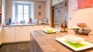 A kitchen with a wooden counter, a sink, and various appliances. There is a window, a door, and a clock on the wall. - Traditional Cottage With Private Terrace (Durbuy)