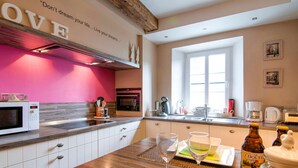 A modern kitchen with white cabinets, a pink accent wall, and a 'LOVE' sign. - Traditional Cottage With Private Terrace (Durbuy)