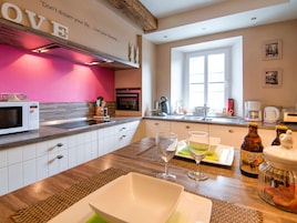 Una cocina moderna con armarios blancos, una pared de acento rosa y un letrero que dice 'LOVE'.