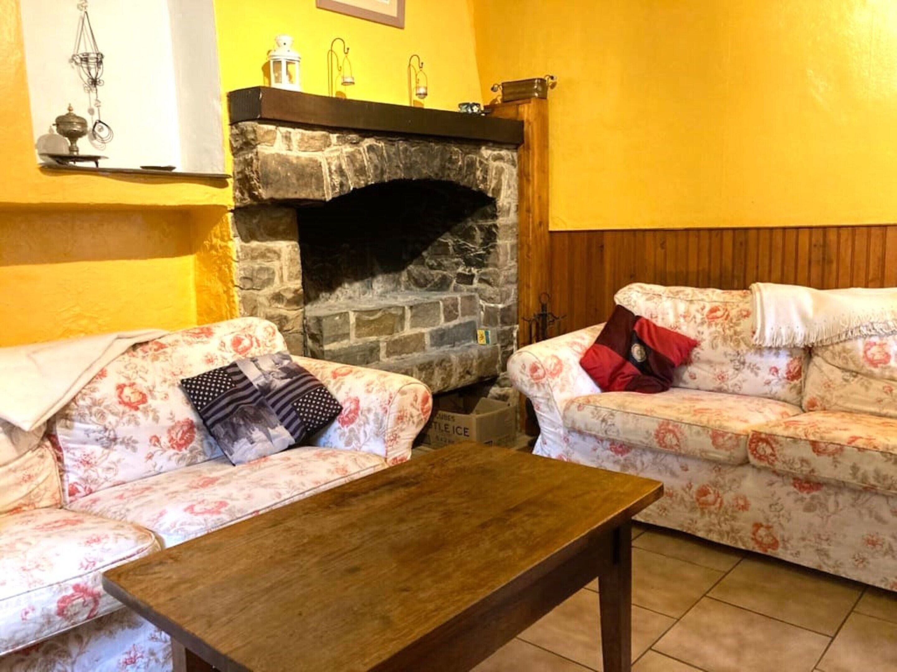 A living room with a stone fireplace, floral sofas, and a wooden coffee table.