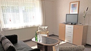 A living room with a sofa, a coffee table, a cabinet, and a television. - Garden Apartment, Gobweinstein (Goessweinstein)