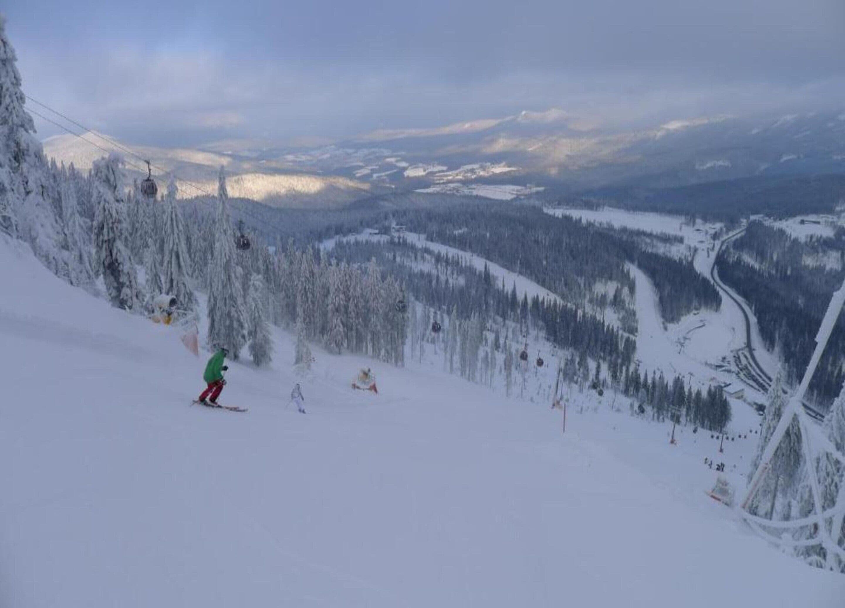 A snowy mountain landscape with ski lifts and a skier.