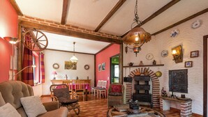 A cozy living room with a wooden ceiling, a fireplace, and a dining area with a table and chairs. - Holiday Home in Waimes With Private Garden (Waimes)
