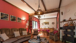 A cozy living room with a sofa, a round table, and a fireplace. - Holiday Home in Waimes With Private Garden (Waimes)