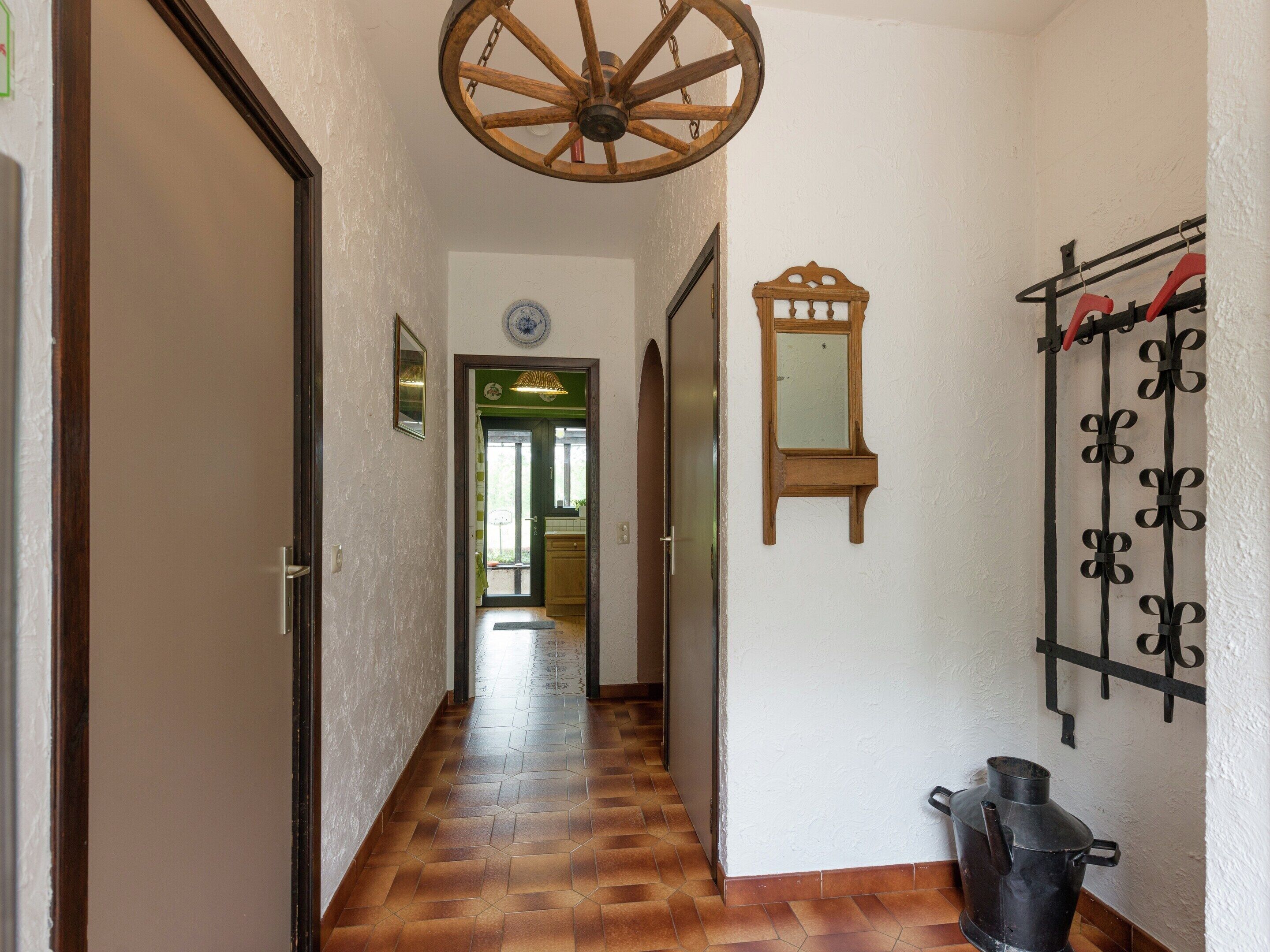 Un couloir avec un ventilateur de plafond en bois, un miroir et un portail en métal.