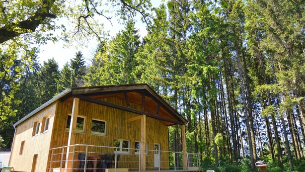 A wooden cabin with a balcony, surrounded by a forest. - Welcoming Cottage in Hatrival With Terrace (Saint-Hubert)