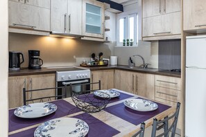 A modern kitchen with wooden cabinets, a gas stove, a sink, and a dining table set with plates.