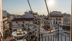 A rooftop terrace with a view of the cityscape, featuring a table with chairs and a railing. - Comfy Central Square Gem with Terrace (Kalamata)