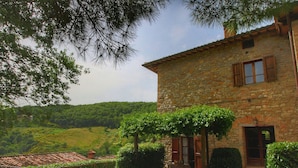 A stone house with a garden, a pergola with climbing plants, and a view of the countryside. - Urban Farmhouse in Umbria With Pool (Monte Santa Maria Tiberina)
