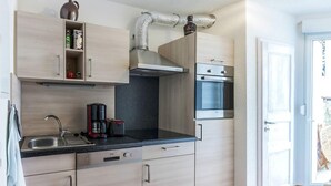 A modern kitchen with light wood cabinets, a stainless steel sink, a coffee maker, and a microwave. - Holiday Home Near the Forest in Thale (Thale)
