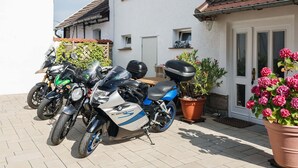 A row of parked motorcycles in front of a house with a tiled roof and a white exterior wall. - Holiday Home Near the Forest in Thale (Thale)