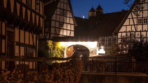 A traditional half-timbered building with a moonlit sky, a stone bridge, and a small tower. - Holiday Home Near the Forest in Thale (Thale)