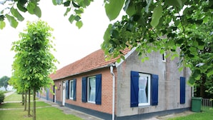 A small brick building with blue shutters, a tiled roof, and a grassy lawn. - Farmhouse in Nederweert Near Canal Trails (Nederweert-Eind)