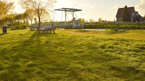 A grassy park with a picnic table, a metal structure, and a house in the background. - Farmhouse in Nederweert Near Canal Trails (Nederweert-Eind)