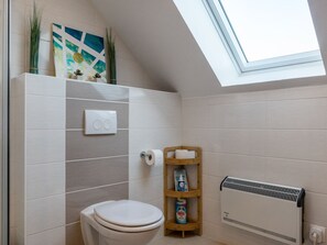 A bathroom with a skylight, a toilet, a shelf with toiletries, and a radiator. - Ferienhaus in Hasselfelde (Oberharz am Brocken)