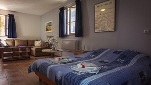 A bedroom with a bed, a sofa, a small table, a lamp, and a map on the wall. - Cozy Cottage Retreat in Vezac (Vezac)