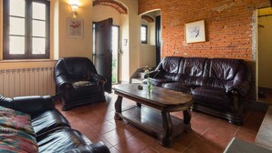 A living room with a brick wall, leather sofas, a wooden coffee table, and a radiator. - Belvilla by OYO Casa Luna (Pescia)