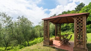 A wooden pergola with a tiled floor and a table and chairs underneath. - Belvilla by OYO Casa Luna (Pescia)