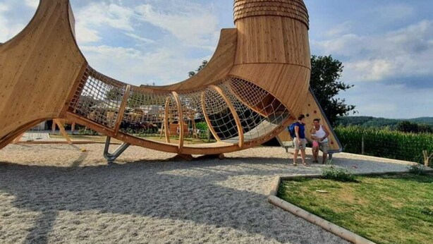 A wooden play structure resembling a ship with a netted enclosure, set in a park with a clear sky. - Woodland Escape With Garden (Neunburg vorm Wald)