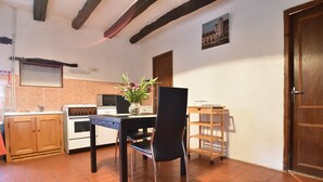 A kitchen with a dining table, chairs, a microwave, an oven, and a wooden cabinet. - Romantic Cottage, Berbiguieres (Allas-les-Mines)