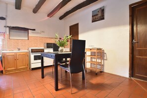 A kitchen with a dining table, chairs, a microwave, an oven, and a wooden cabinet. - Romantic Cottage, Berbiguieres (Allas-les-Mines)