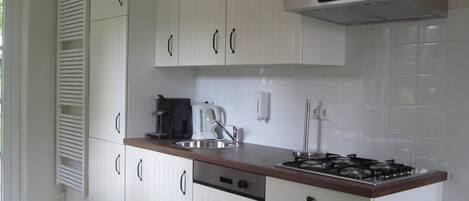 Una cocina moderna con armarios blancos, estufa de acero inoxidable y cafetera.