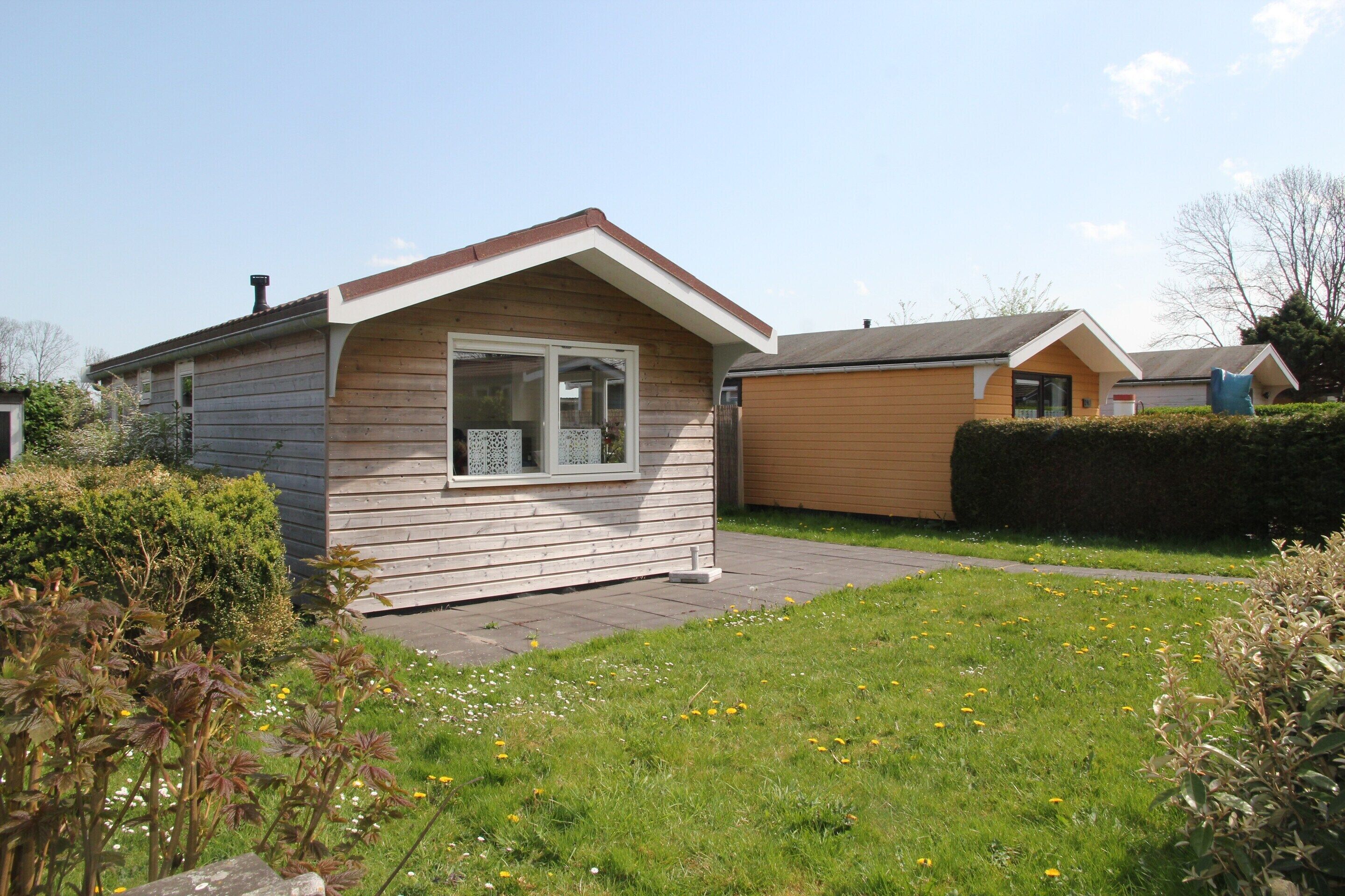 A two-story wooden house with a sloped roof and a small front yard.