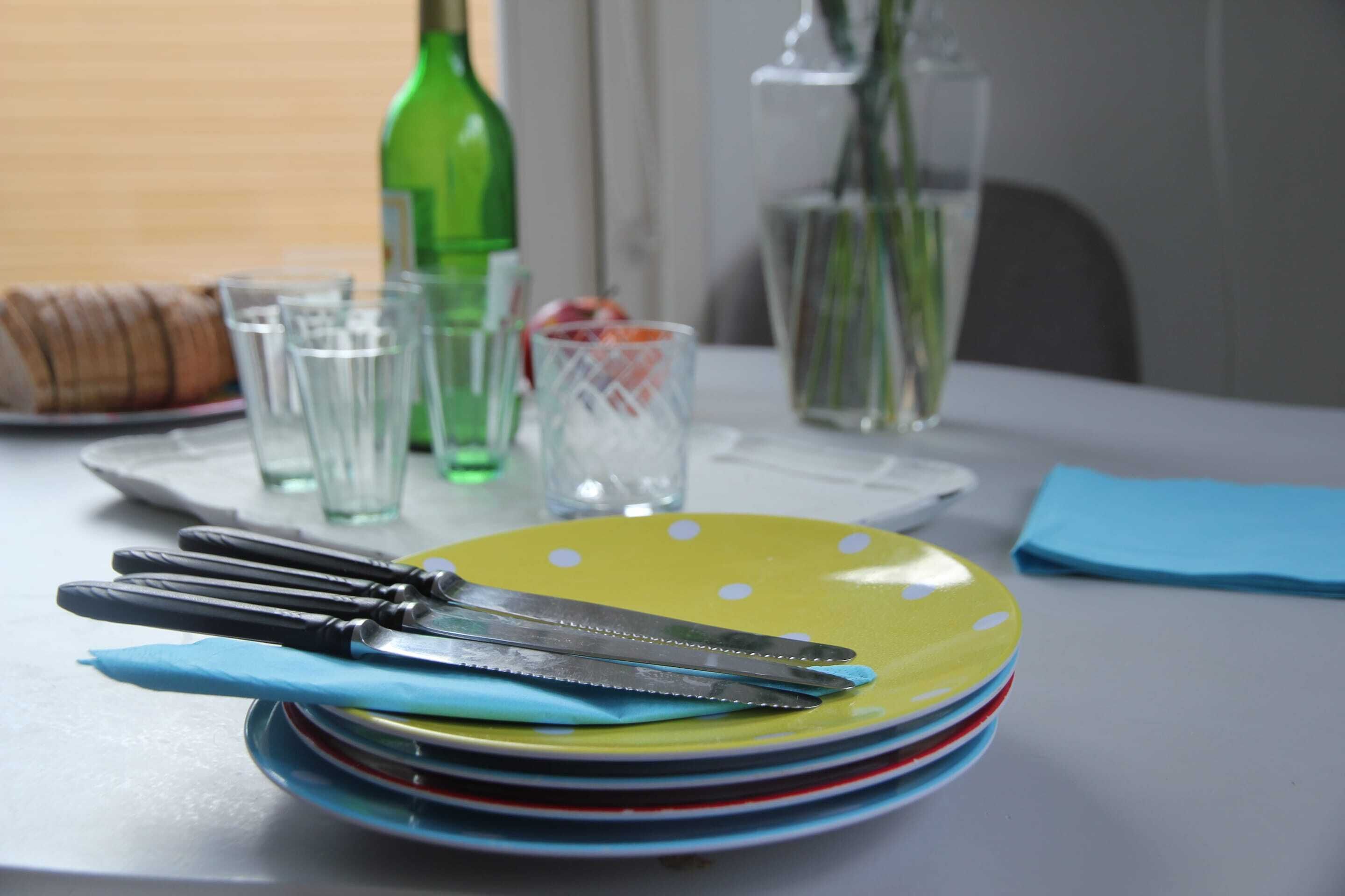 A table set with plates, cutlery, glasses, and a bottle.