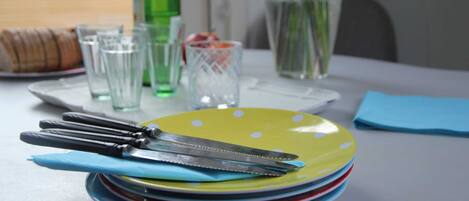 A table set with plates, cutlery, glasses, and a bottle.