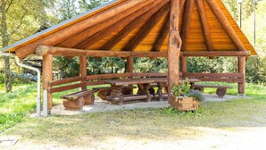 Un pavillon rustique en bois, doté d’un toit incliné, de bancs et de tables de pique-nique.