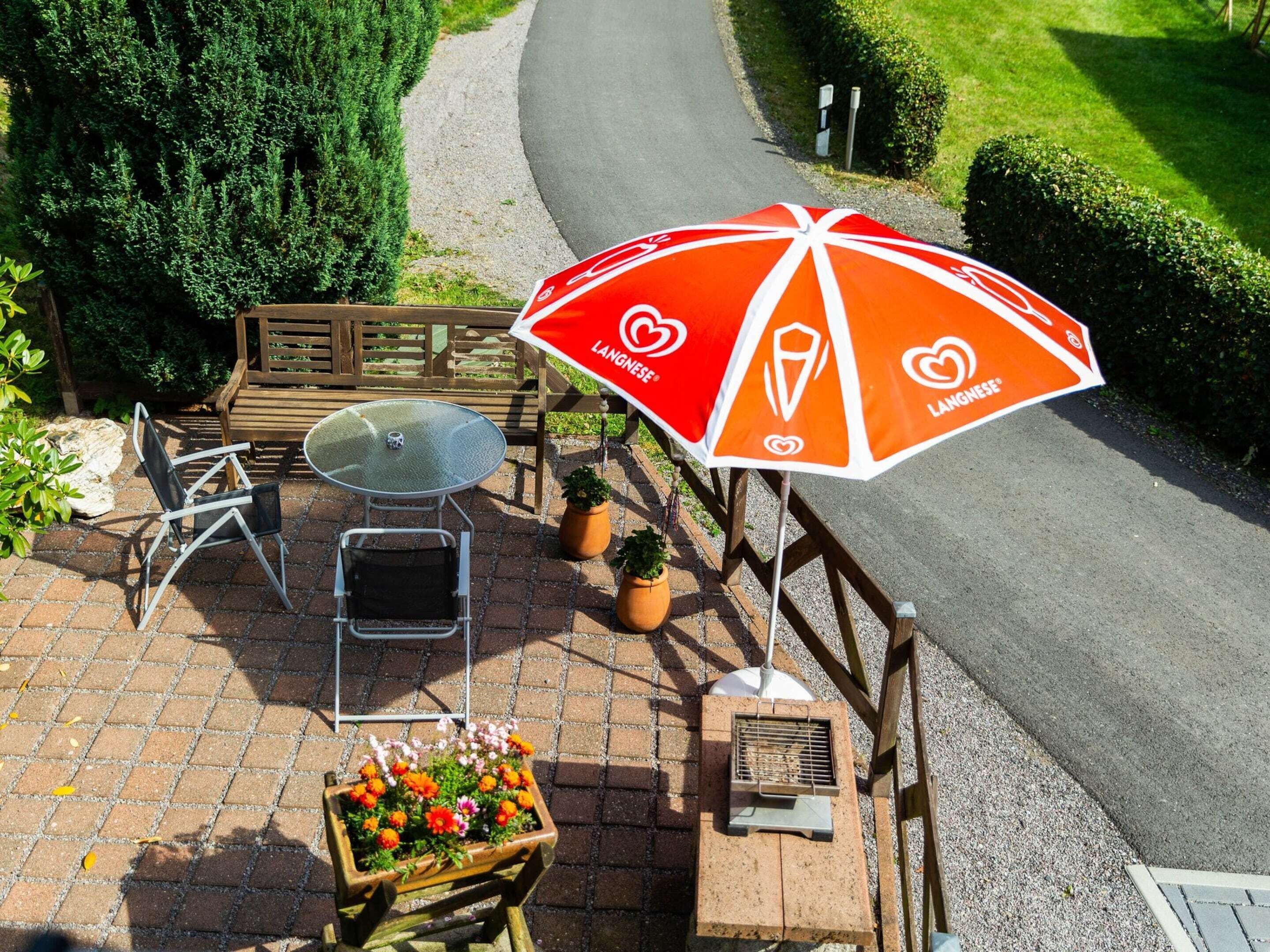 An outdoor seating area with a table, chairs, an umbrella, and potted plants.