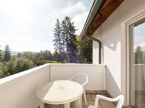 A balcony with a table and two chairs, overlooking a forested area. - Spa Apartment, Bad Durrheim (Bad Duerrheim)
