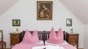 Ein Schlafzimmer mit kariertem Bettbezug, zwei Kissen, einem hölzernen Kopfteil, einem Nachttisch mit Lampe und einem gerahmten Gemälde an der Wand.