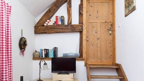 Ein gemütliches Zimmer mit Schreibtisch aus Holz, Fernseher und Bücherregal.