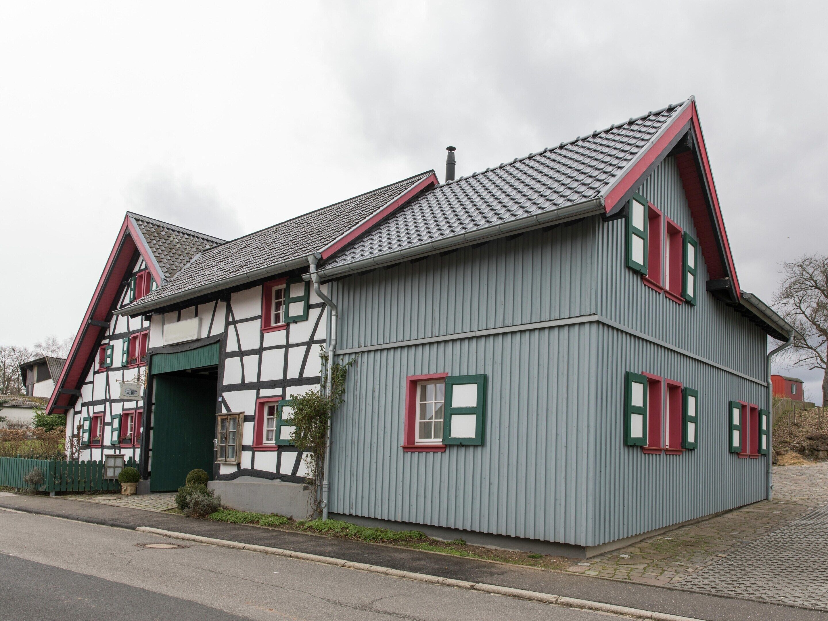 A traditional half-timbered house with a steeply pitched roof and red window shutters.