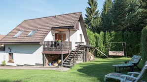 A two-story house with a balcony, a wooden deck, and a swing set in the backyard. - Holiday Home Beerheide Near Ski Slopes (Auerbach)